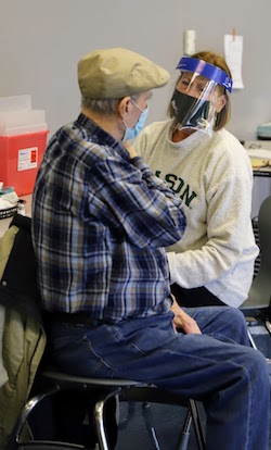 Dr. Germaine Louis gives a patient a COVID-19 vaccine at Mason's vaccination event with the Prince William Health Department 